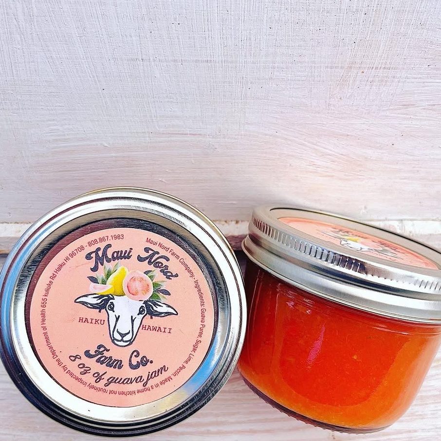 Two jars of guava jam on a white board, one open, showing the jam