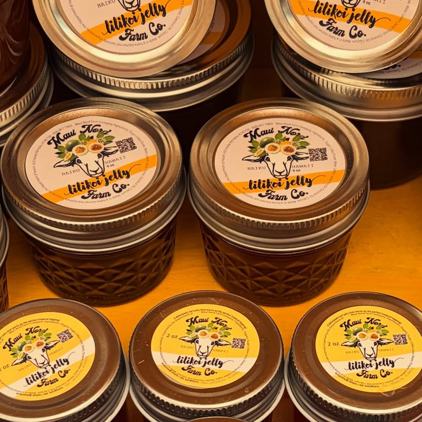 Jars of lilikoi jelly stacked on a shelf, yellow labels on the lids