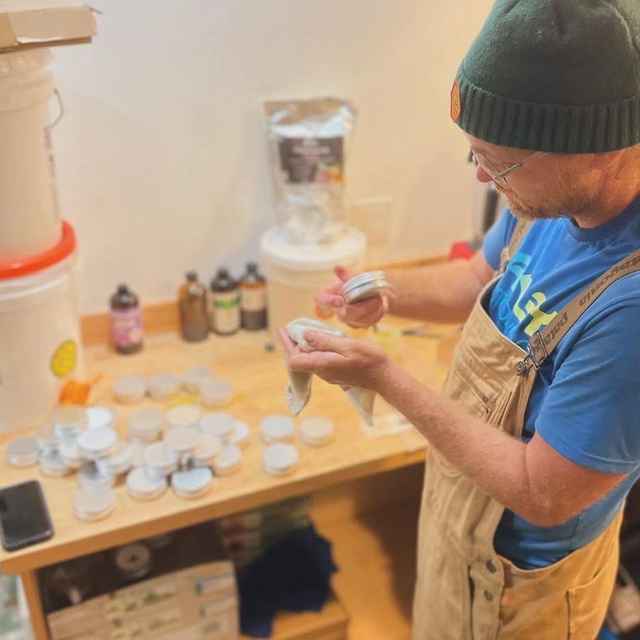 A man in overalls sorting jar lids at a workbench